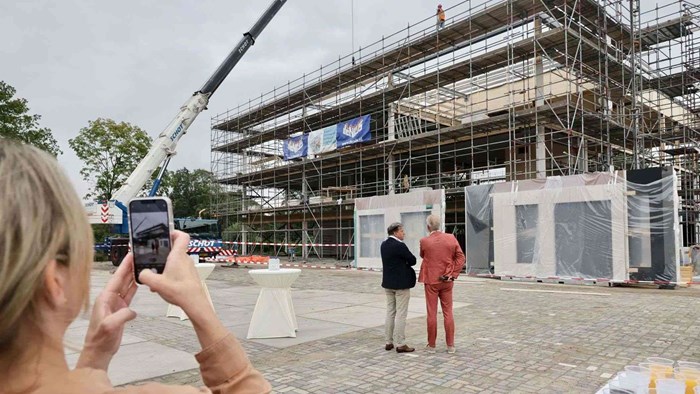 Het laatste dak-element wordt op het sport- en zorghuis gehesen. Op de voorgrond kijken wethouder Ren&#233; Assendelft en centrumdirecteur Leen Koole toe.